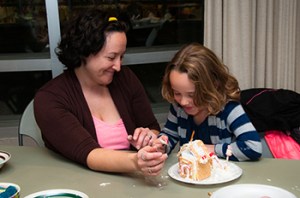 A parent and child works on a gingerbread house together at the Longmont Library