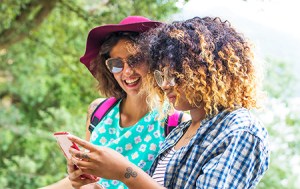 Two happy friends looking at a cell phone for an excursion