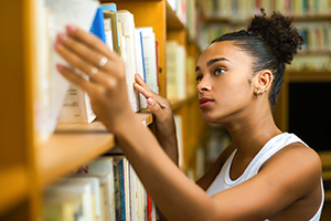 A black teen shelves books at the library