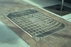 a photo of a sidewalk with a recessed bronze map of Longmont is shown.