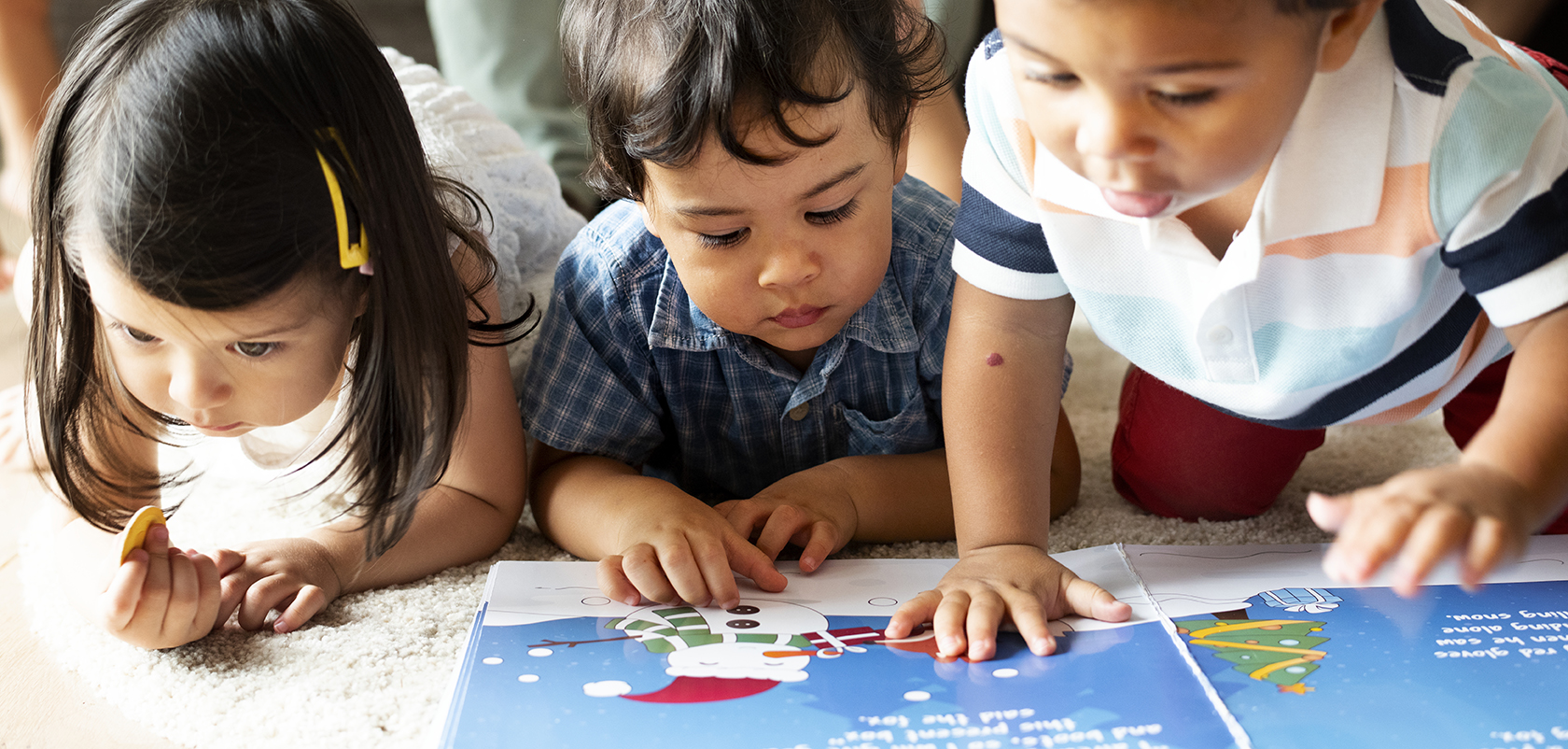 Children reading a book on the floor