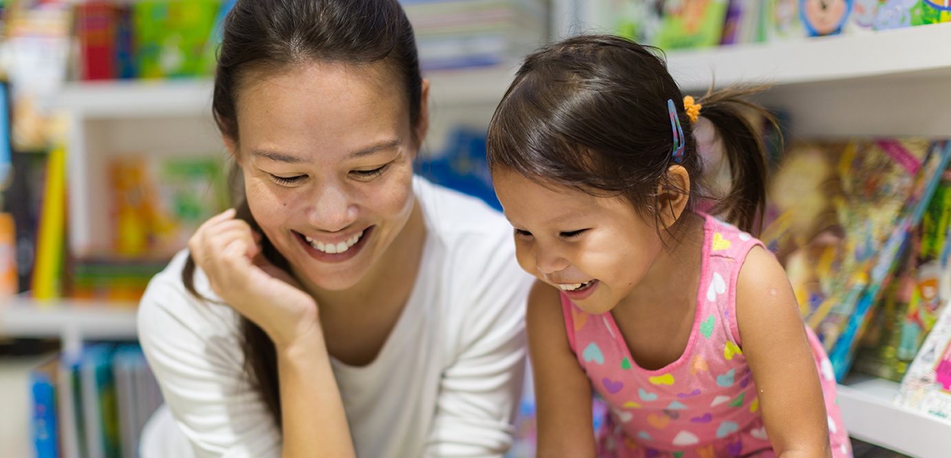 Parent and child reading books together in the library.