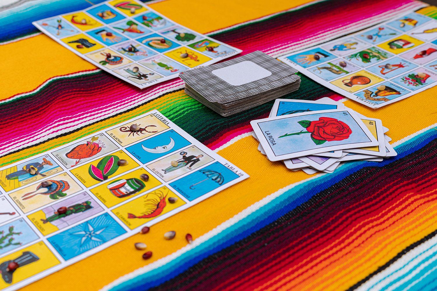 Loteria cards are shown on a Mexican blanket