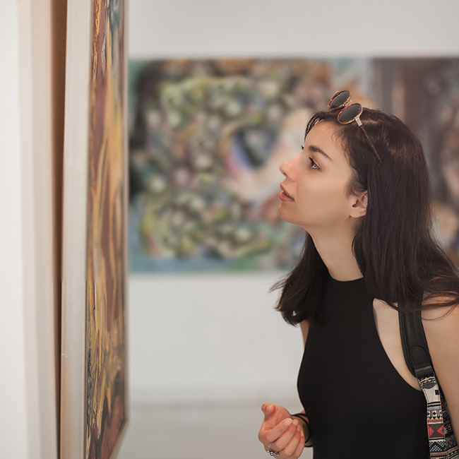 Young woman looking at modern painting in art gallery