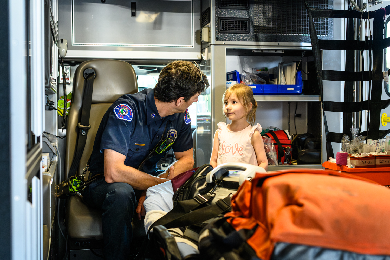 Firefighter Paramedic talks with young girl at open house