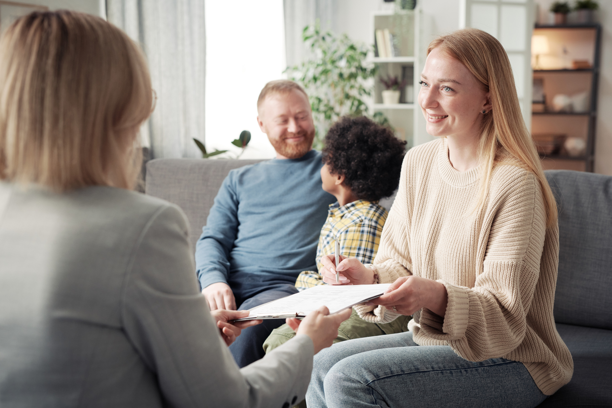 Young woman signing energy efficiency paperwork while young man smiles at their child.