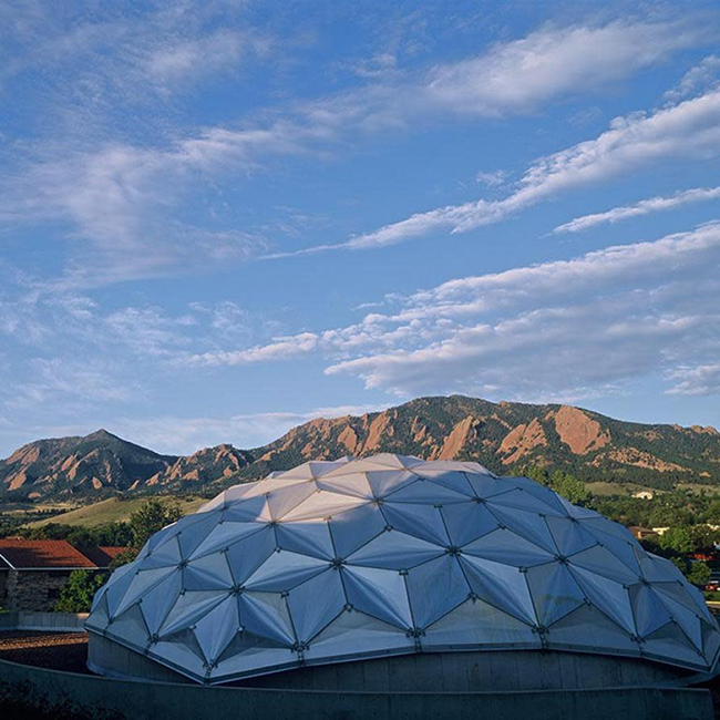 The outside of the Fiske Planetarium is shown with the flatirons in the background