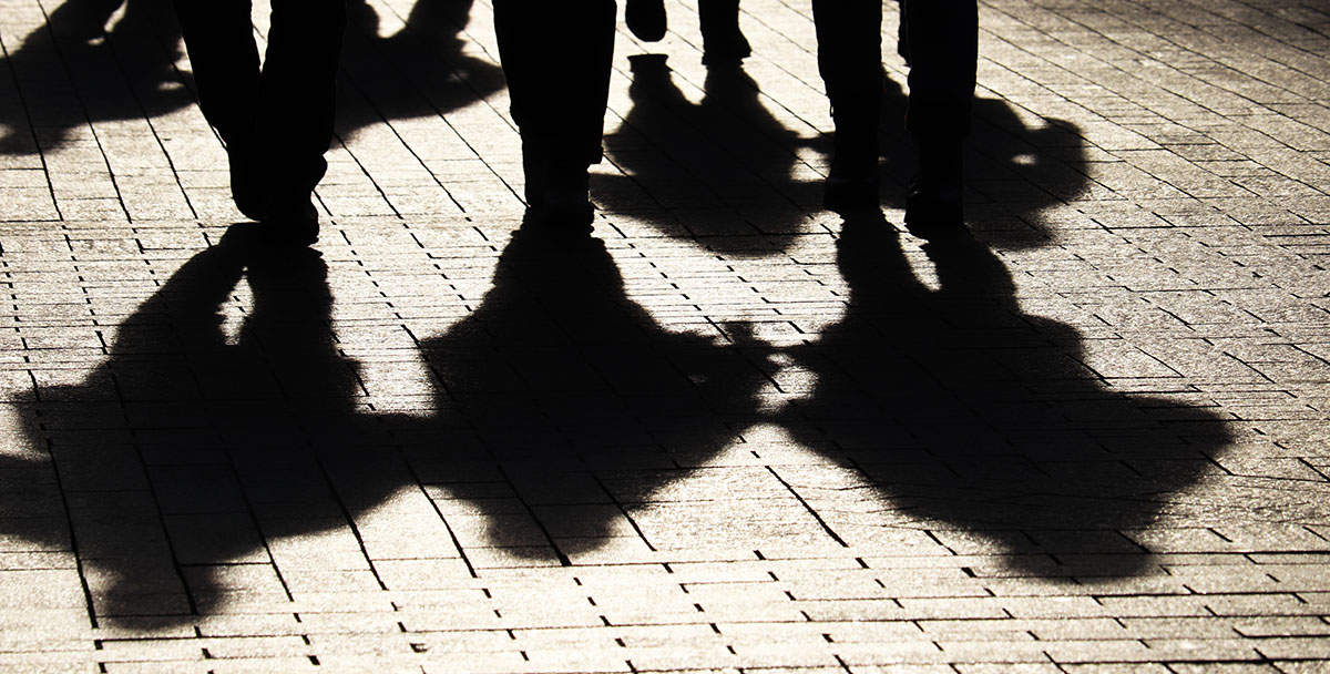 The shadows of a group of people are seen on a nightitme city street.