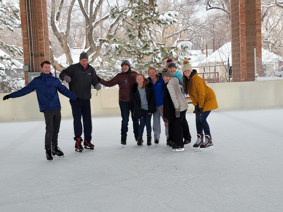 Group of adults on ice skates smiling while posing for photo