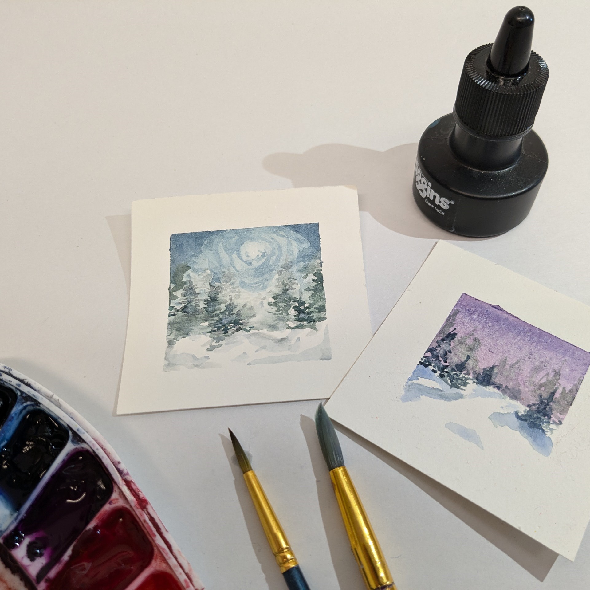 Watercolor painting of snowy trees with paint brush and palette