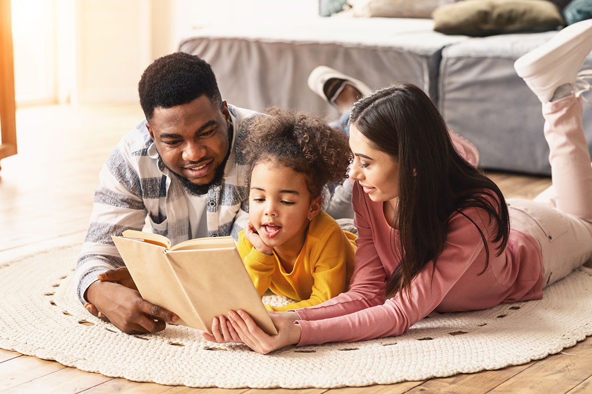 A man and a woman read to a small child.