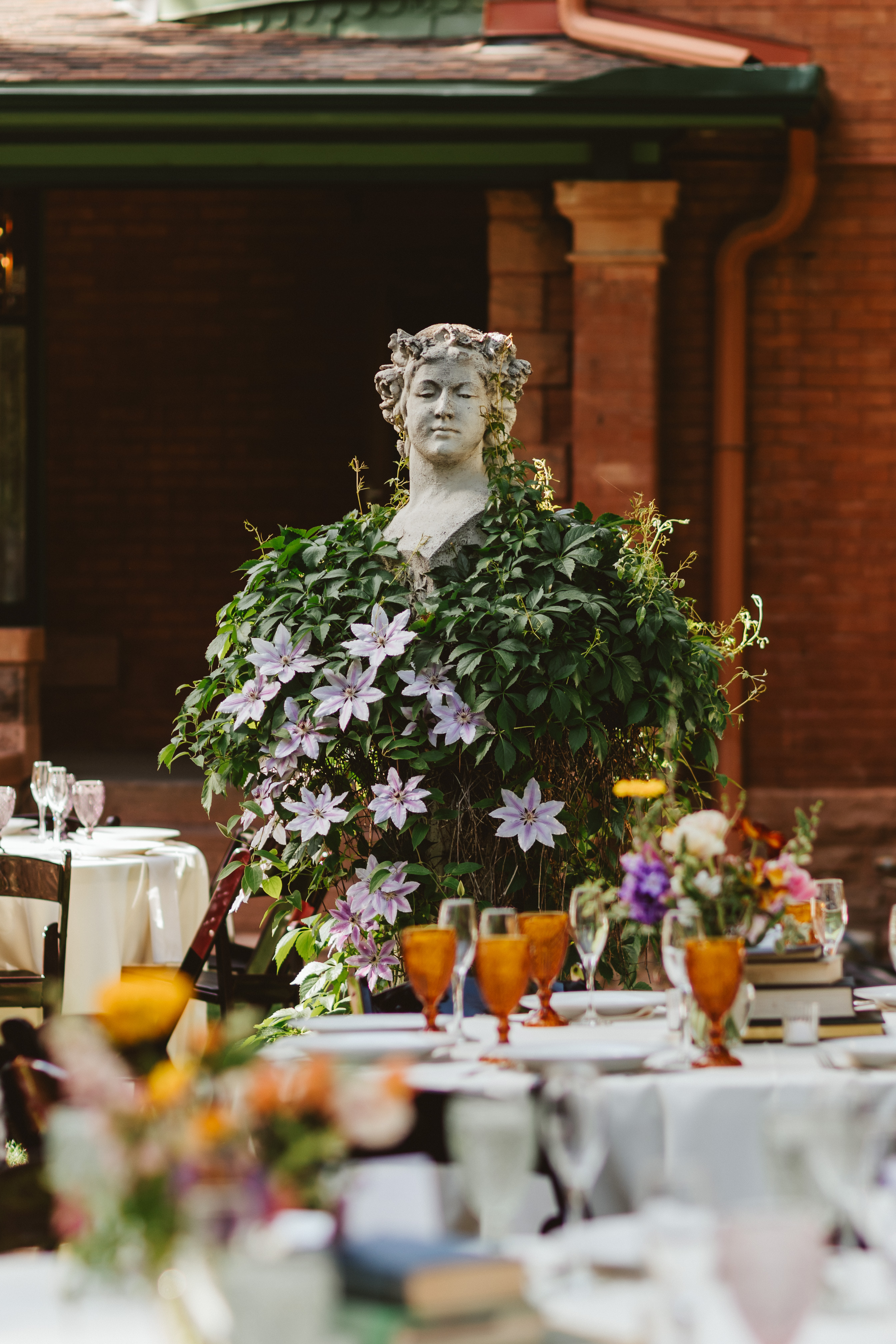 Table settings for wedding featuring a statue and blooming flowers in the background.