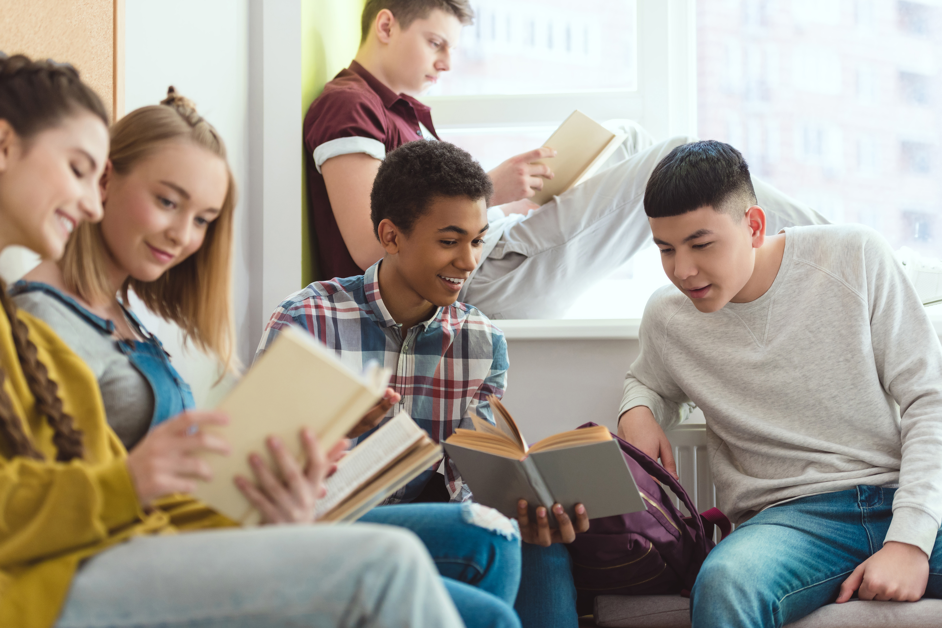 Smiling multicultural schoolchildren doing homework during school break