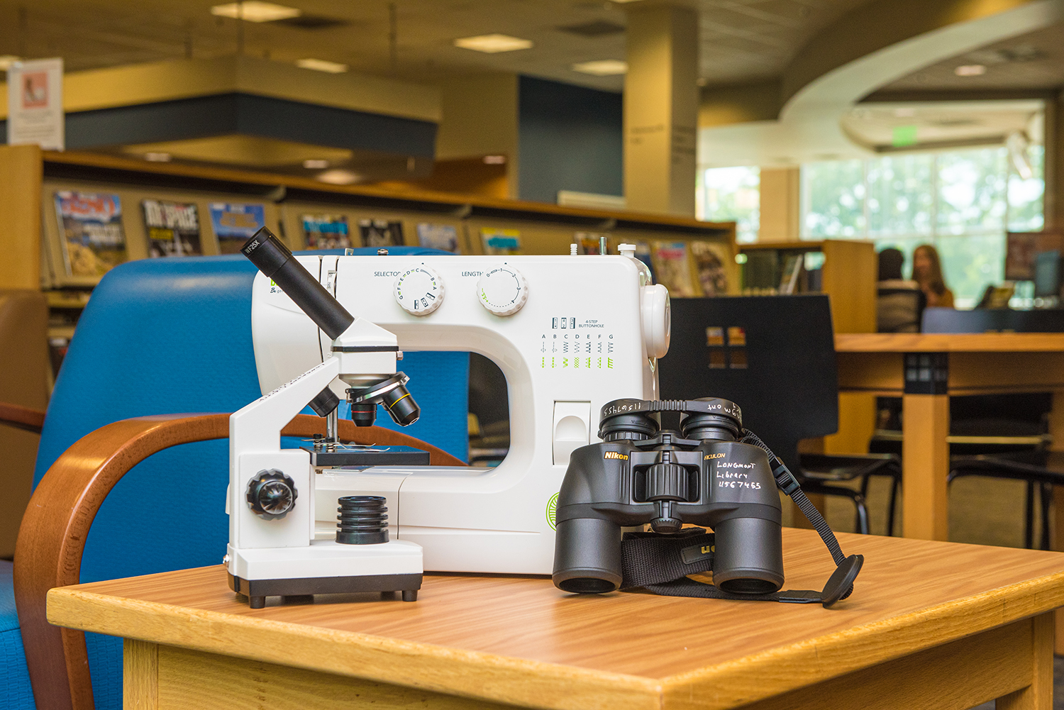 A sewing machine, binoculars and a microscope are displayed on a table